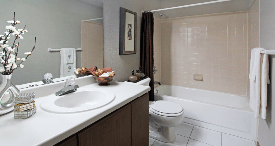 Spacious bathroom with lots of cabinet space, tiled floor, tiled shower, extra cabinet space, and gray wall color at The Vanderbilt Apartments in Omaha, Nebraska