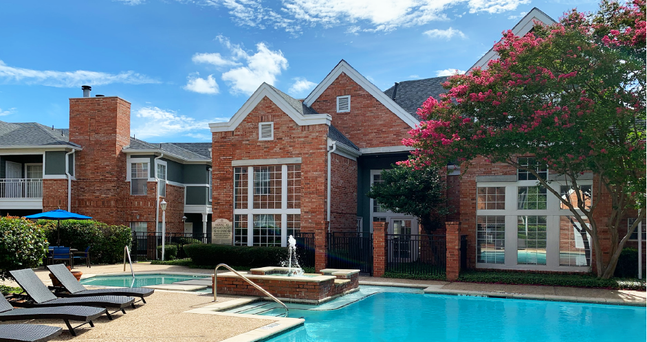 Luxury apartments with two resort-style swimming pools with fountain, poolside lounge chairs, and beautiful landscaping in Dallas.