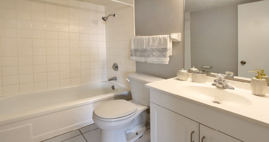 Bathroom with white cabinets, tiled floor, tiled shower with tub, and gray wall color at The Inverness Apartments in La Vista, Nebraska