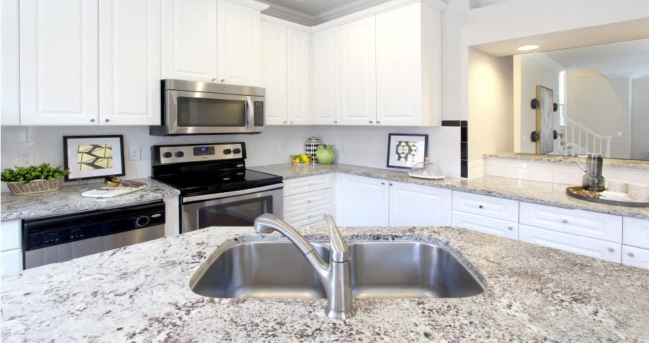 Spacious kitchen with island, granite countertops, white cabinets, smooth glass top stove, spacious pantries, breakfast bar and stainless-steel appliances at Tuscany Villas in Houston.