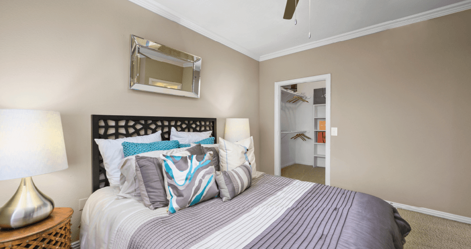 Spacious bedroom with walk-in closet and ceiling fan at Tuscany Park Apartments in Houston.