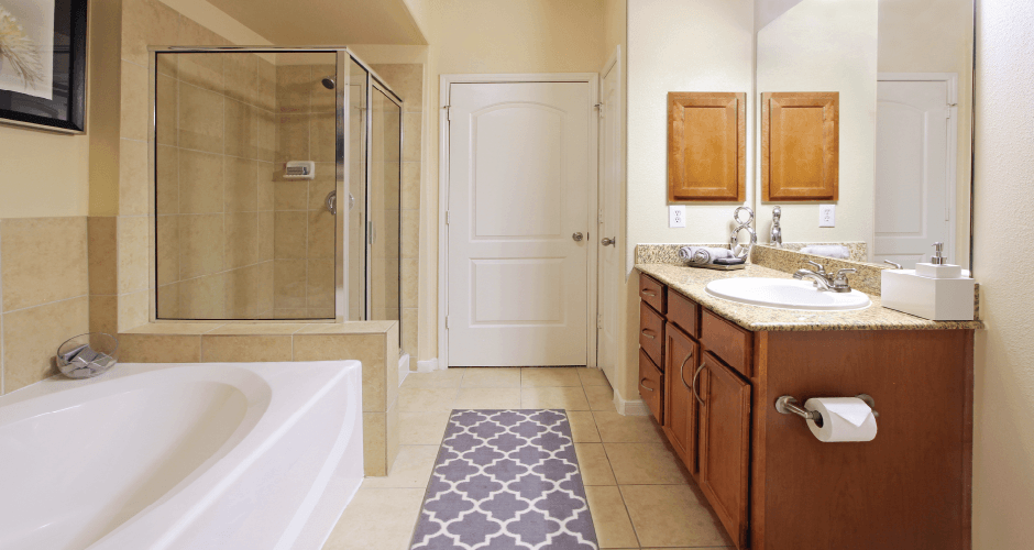 Spacious master bathroom with oval soaking tub, separate glass shower, and spacious linen closet at The Voss Apartments in Houston.