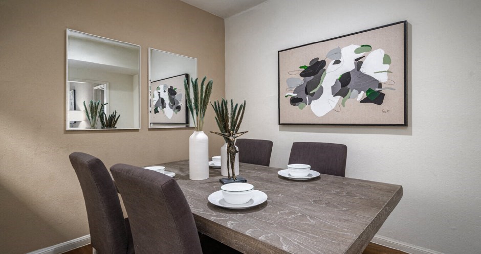 Dining area with painted feature wall and wood plank floors at Woodlake on the Bayou Apartments