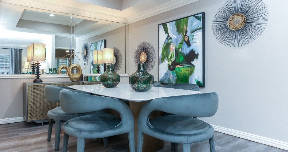 Dining room with mirror accent wall, recessed ceiling, wood plank floors, gray colored walls at The Dorchester Apartments in Dallas Texas