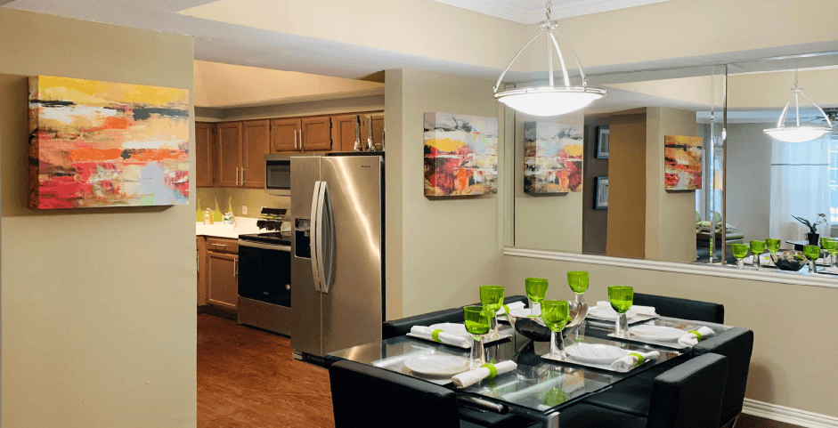 Spacious dining room with 9-foot ceilings, mirror accent wall, stainless steel appliances, side-by-side refrigerators at The Lanesborough Apartments in Houston.