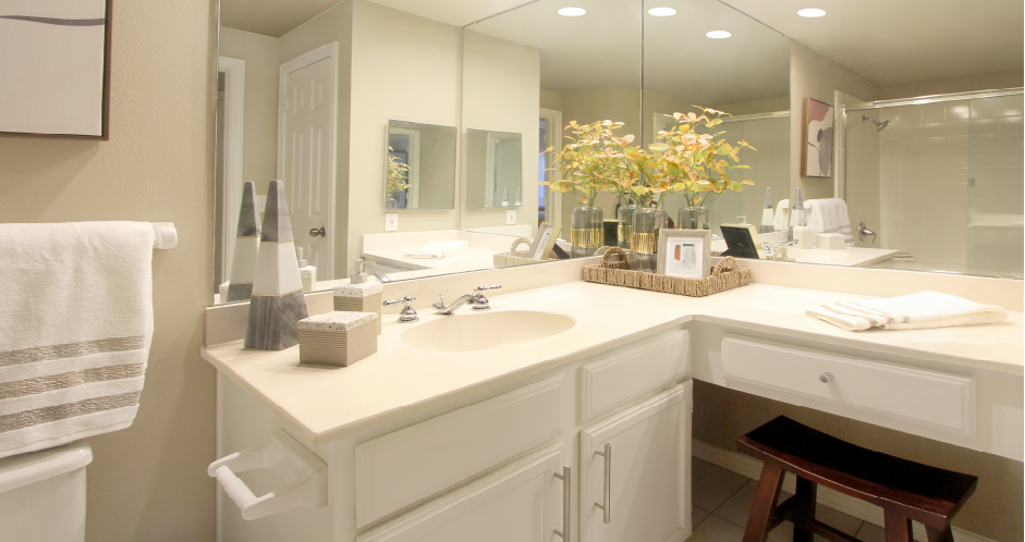 Spacious bathroom with oval soaking tub, glass shower, cultured marble vanity, and built-in vanity at The Dorchester Apartments in Houston.