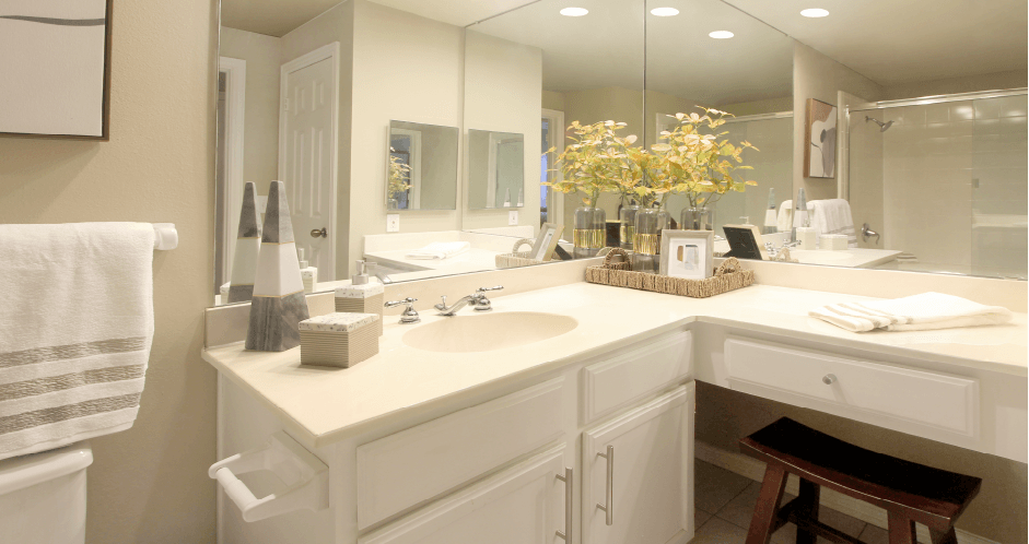 Spacious bathroom with oval soaking tub with glass enclosure, cultured marble vanity, glass shower, and built-in vanity at Tuscany Lane Apartments in Houston.