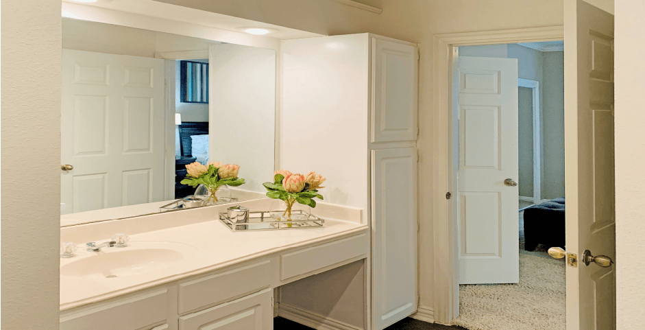 Spacious bathroom with cultured marble vanity, spacious linen cabinet, white cabinets, and built-in vanity at The Lanesborough Apartments in Houston.
