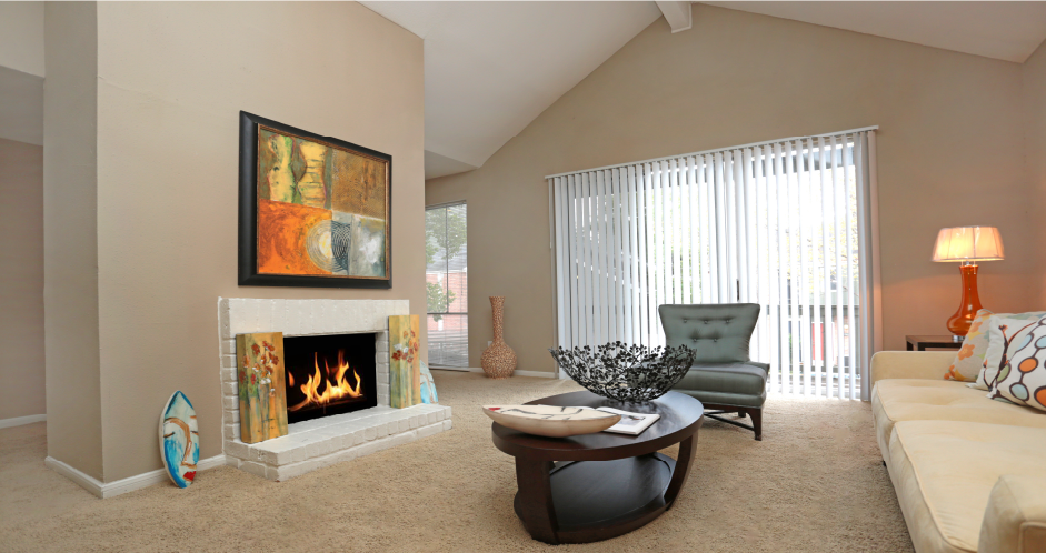Spacious floor plan with vaulted ceiling, woodburning fireplace, and oversized windows at Woodlake on the Bayou Apartments in Houston.