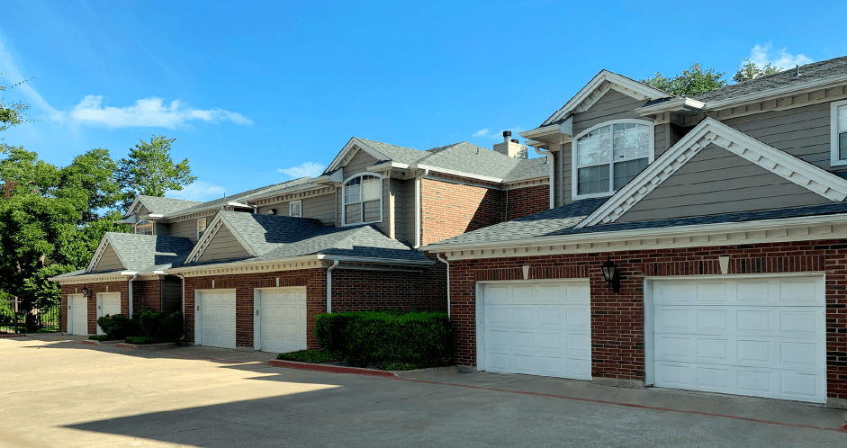 Luxury apartments in a gated community with red brick exteriors and attached garages at Prestonbridge Apartments in North Dallas