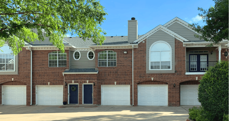 Luxury apartments in a gated community with red brick exteriors and attached garages at Prestonbridge Apartments in North Dallas