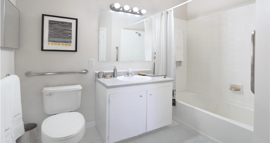 Spacious bathroom with white cabinets, linen closet, extra cabinet space, soaking tub and tiled shower at Breckenridge Apartments in Omaha, Nebraska