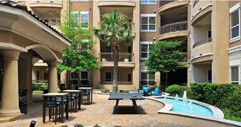 Luxury apartments with palm trees, spacious sundeck with poolside lounge chairs, grilling station, ping-pong table, and fountains at Villa Piana Apartments in Dallas - Photo Gallery 19