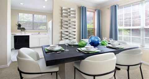 Spacious dining room with oversized windows, u-shaped kitchen with white cabinets, and side-by-side refrigerator at TurtleCreek apartments in West Des Moines, Iowa
