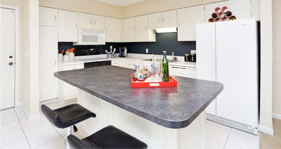 Large kitchen with lots of cabinet and counter space, white cabinets, colored feature wall, kitchen island, and prep island at Embassy Park Apartments in Omaha, Nebraska