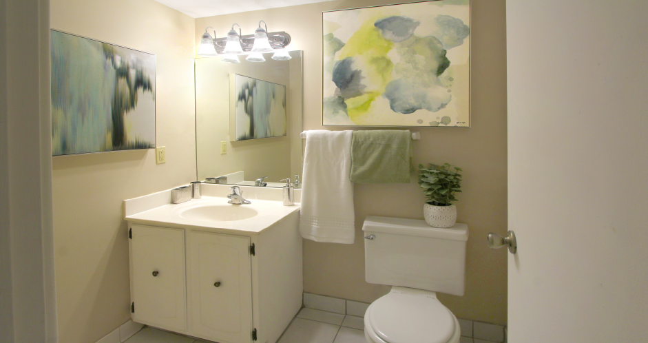 Half Bath with white cabinets and tiled floor at Alpine Village Apartments in La Vista, Nebraska