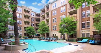 Luxury apartments with resort-style pool, palm trees, spacious sundeck with poolside lounge chairs, grilling station, fountains, and fitness center at Villa Piana Apartments in Dallas - Photo Gallery 27