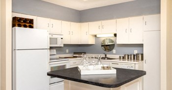 Kitchen with white cabinets, lots of cabinet space, kitchen island, prep island, and colored feature wall at Embassy Park Apartments in Omaha, Nebraska