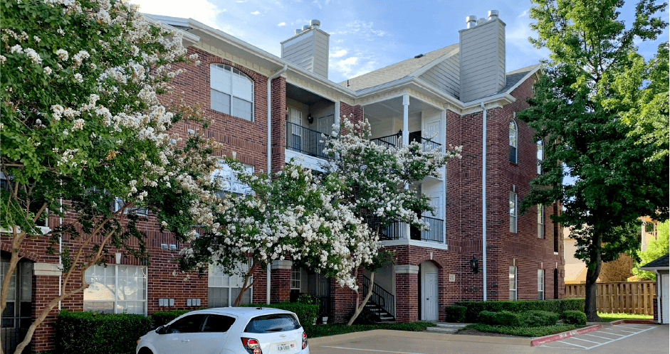 Luxury apartments in a gated community with red brick exteriors and beautiful landscaping at Prestonbridge Apartments in North Dallas