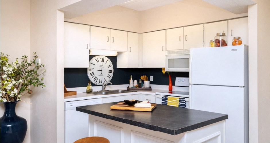 Kitchen with white cabinets, lots of cabinet space, kitchen island, prep island, and colored feature wall at Embassy Park Apartments in Omaha, Nebraska