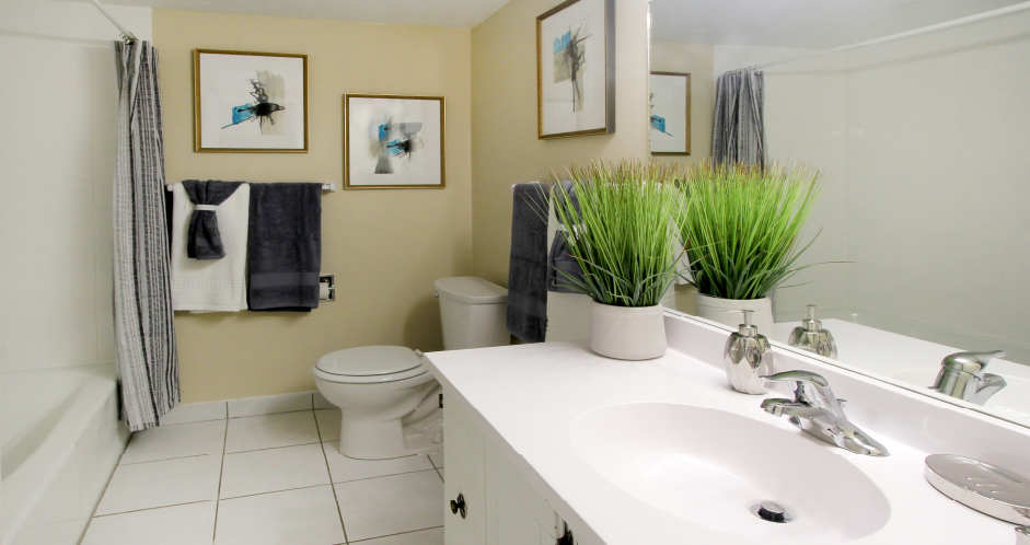 Spacious bathroom with white cabinets, tile floor and tiled shower with tub at Alpine Village Apartments in La Vista, Nebraska