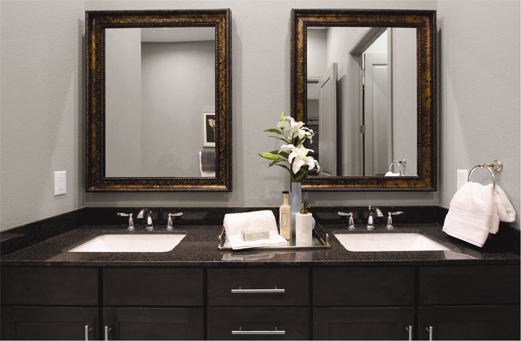 Double vanity bathroom with two mirrors and a black granite vanity top