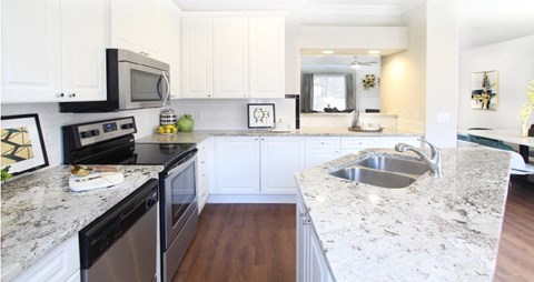 Spacious kitchen with island, granite countertops, white cabinets, smooth glass top stove, spacious pantries, breakfast bar and stainless-steel appliances at Tuscany Villas in Houston.