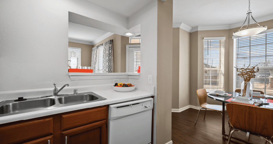 Spacious dining room with large bay windows and wood plank floors at Tuscany Park Apartments in Houston.