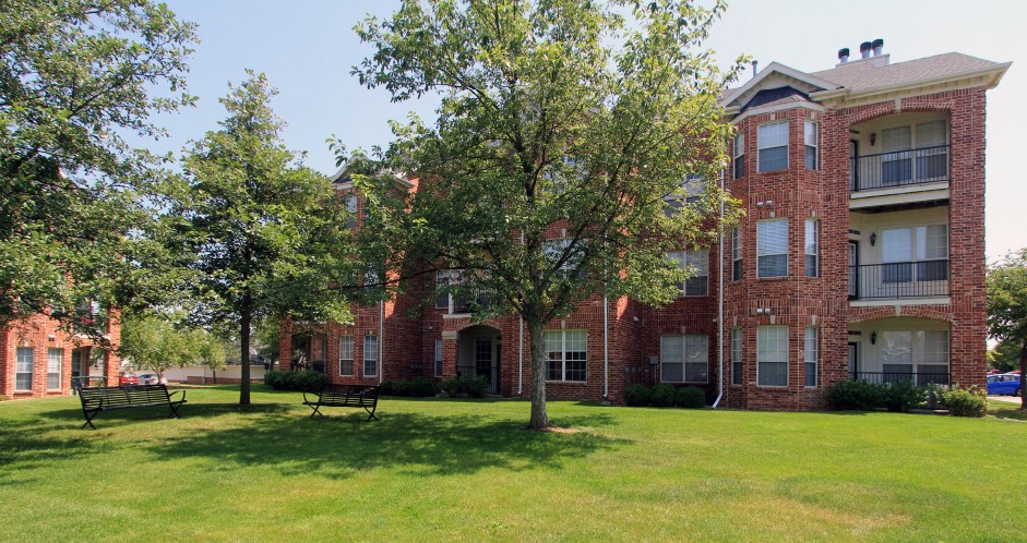 Luxury apartments with red brick exterior, spacious balconies, lush landscaping, park-like setting, and scenic views at Lenox Village Apartments in Lincoln, Nebraska