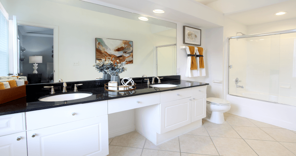 Spacious master bathroom with granite countertops, double sink vanity, double mirror vanity, and oval soaking tubs with glass enclosures at Tuscany Row Townhomes in Houston.