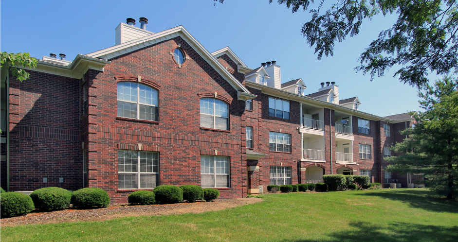 Luxury apartments with red brick exteriors, attached garages, spacious balconies, lush landscaping, and scenic views at Saddlebrook apartments in Urbandale Iowa