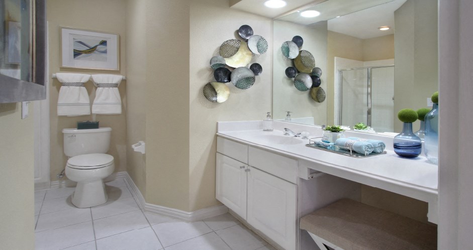 Luxury bathroom with white cabinets, cultured marble vanity, linen closet, and glass shower at Saddlebrook apartments in Urbandale Iowa