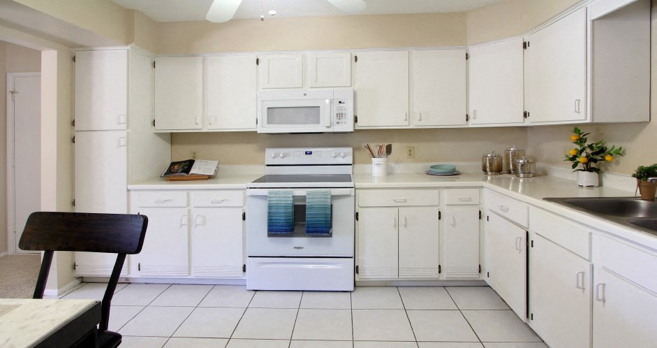 Spacious kitchen with lots of cabinet space, lots of counter space, white kitchen cabinets, bright white kitchen, porcelain tile floor, huge kitchen at Alpine Village Apartments in La Vista, Nebraska