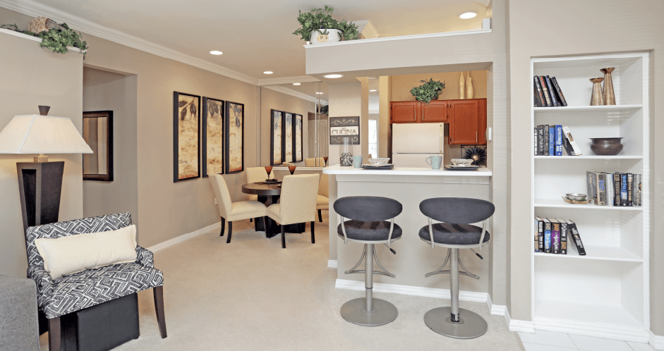 a living room with a table and chairs and a kitchen in the background