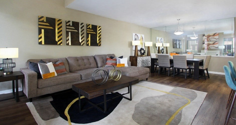 Spacious floor plan with wood plank floors, mirror accent wall, oversized windows, and lots of natural light at Woodlake on the Bayou Apartments.