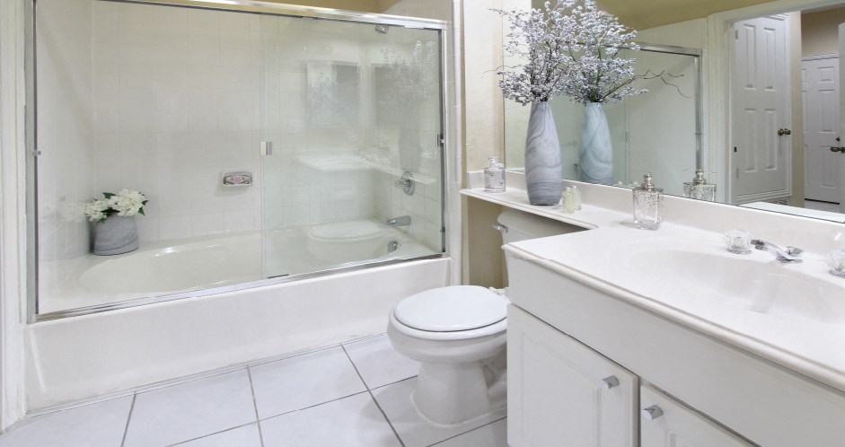 Luxury bathroom with tiled floors, oval soaking tub, built-in vanity, cultured marble vanity, glass shower and white cabinets in at TurtleCreek apartments in West Des Moines, Iowa