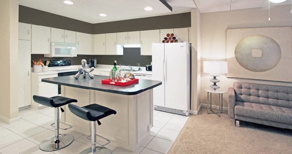 Large kitchen with lots of cabinet and counter space, white cabinets, colored feature wall, kitchen island, and prep island at Embassy Park Apartments in Omaha, Nebraska