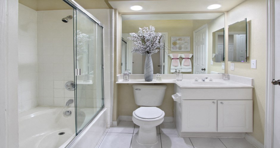 Luxury apartments with spacious bathrooms with tiled floors, oval soaking tub, built-in vanity, cultured marble vanity, glass shower and white cabinets in at Saddlebrook apartments in Urbandale Iowa