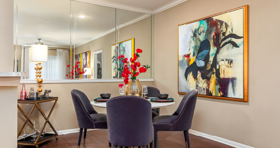 Luxury apartments with spacious dining room, wood plank floors, breakfast bar, mirror accent wall, and 9-foot ceilings at Kensington Square Apartments.
