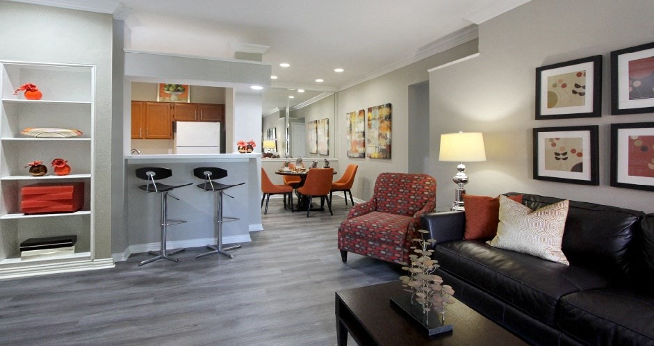 Luxury apartments with wood grain plank floors, dining room, u-shaped kitchen, mirror accent wall, built-in shelves, and breakfast bar at Lenox Village Apartments in Lincoln, Nebraska