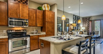 Luxury apartments next to the Galleria in Dallas with granite countertops, stainless steel appliances, built-in wine rack, kitchen island, and porcelain tile floor at Villa Piana Apartments in Dallas - Photo Gallery 2