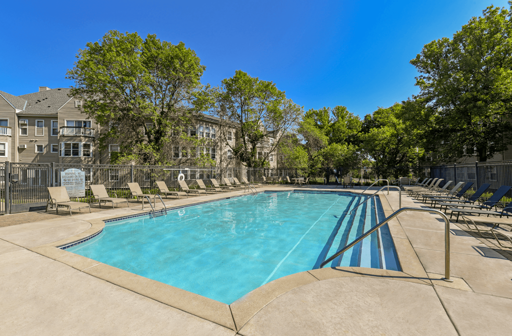 Apartments set in a nature preserve with a huge swimming pool with poolside lounge chairs and scenic views at Claremont Apartments in Minnetonka Minnesota