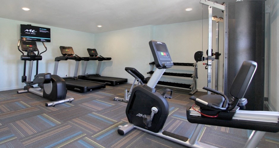 A gym with a treadmill, elliptical trainer, and other exercise equipment.