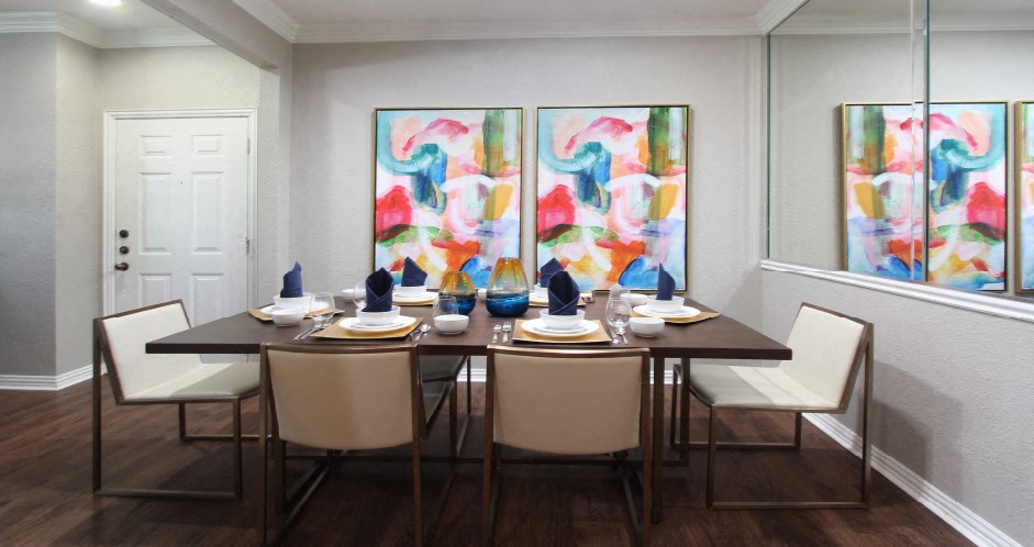 Luxury apartments with spacious dining room, mirror accent wall, and wood grain plank floors at Lenox Village Apartments in Lincoln, Nebraska