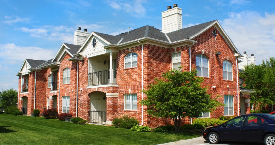 Luxury apartments with red brick exterior, spacious balconies, lush landscaping, park-like setting, and scenic views at Lenox Village Apartments in Lincoln, Nebraska