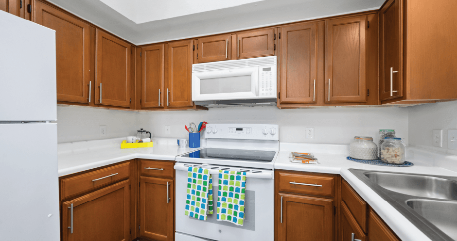 Spacious kitchen with custom home cabinets, recessed ceiling, and side-by-side refrigerator at Tuscany Park Apartments in Houston.