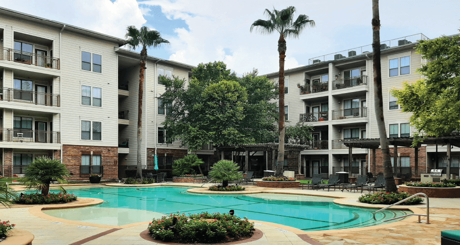 Luxury swimming pool with cabanas, poolside lounges, grilling stations, palm trees and beautiful landscaping at The Voss Apartments in Houston.