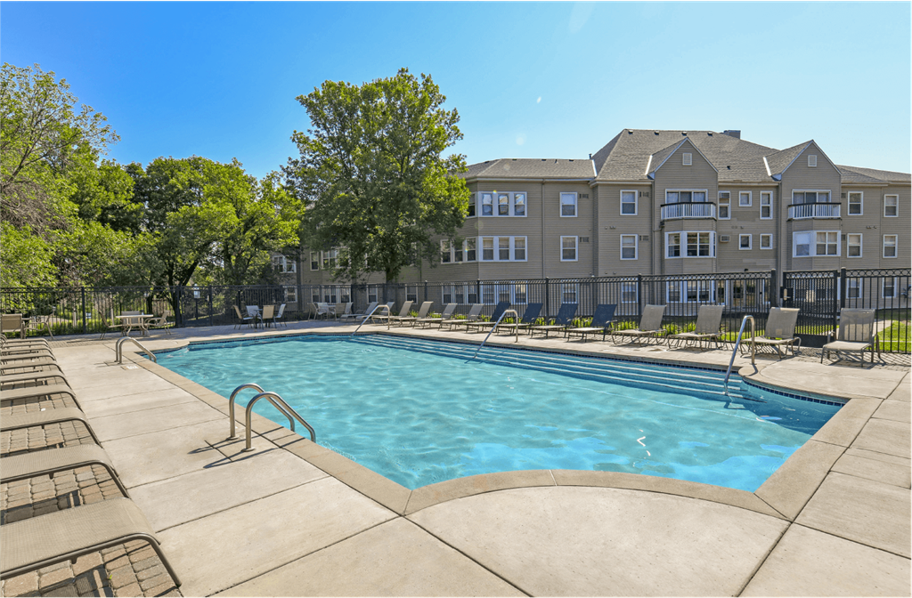 Apartments set in a nature preserve with a huge swimming pool with poolside lounge chairs and scenic views at Claremont Apartments in Minnetonka Minnesota