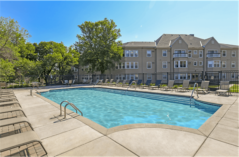 Apartments set in a nature preserve with a huge swimming pool with poolside lounge chairs and scenic views at Claremont Apartments in Minnetonka Minnesota