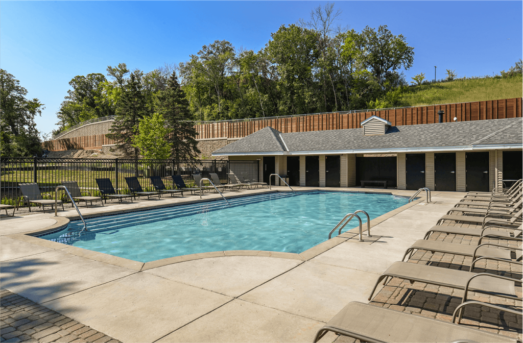 Apartments set in a nature preserve with a huge swimming pool with poolside lounge chairs and scenic views at Claremont Apartments in Minnetonka Minnesota